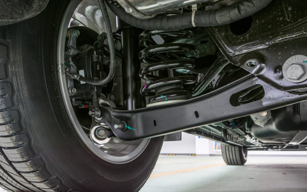 Close-up of a car's suspension system, showcasing the tire, shock absorber, and various parts of the undercarriage in intricate detail.