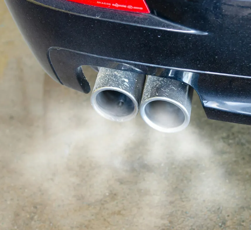 Car exhaust pipes emitting visible smoke onto the ground.