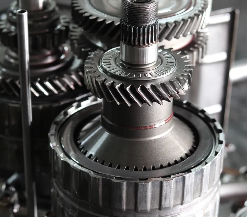 transmission-2 Close-up of metal gears and shafts in a mechanical assembly, likely part of an engine or gearbox.